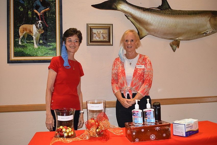 Paula Sharp and Sue DiNatale keep track of how many people have gone in or out with two vases of ornaments as counting measures.
