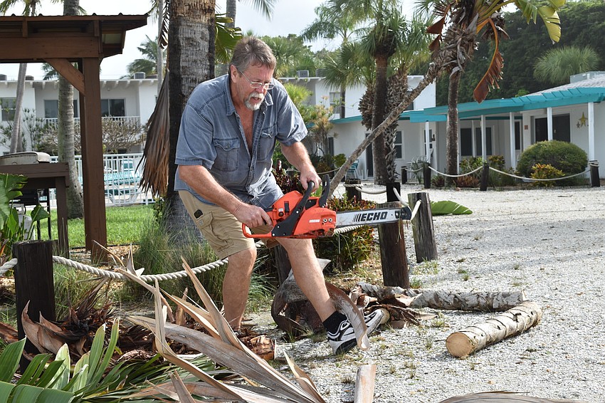A worker at Sea Club Beach Resort works to remove some downed trees and debris after Eta passed through on Wednesday night.