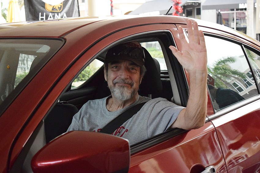 Sabal Harbour's Joe Angers waves to volunteers as he goes through the drive-thru. Angers usually volunteers for Empty Bowls but couldn't because of COVID-19.