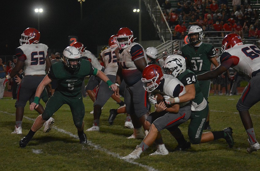 Lakewood Ranch junior defensive lineman Kaden Rathburn (24) tackles Manatee quarterback Jayse Berzowski.