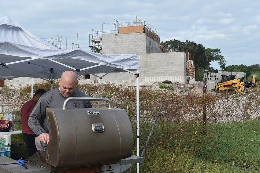 Bryan Carr grills behind the in-progress south fire station.