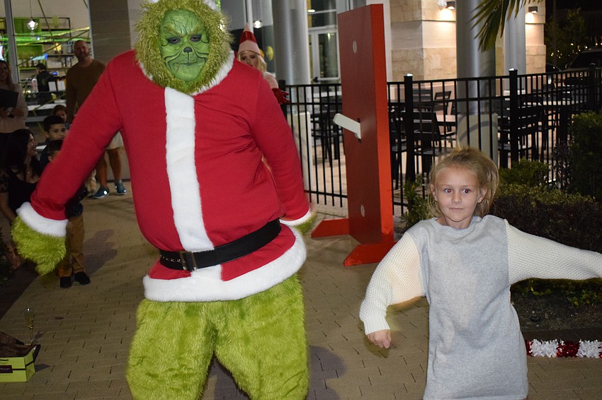 The Grinch, played by Chris Cude of Legendary Knights Entertainment of Winter Haven, dances with East County 6-year-old Mallory Clark.
