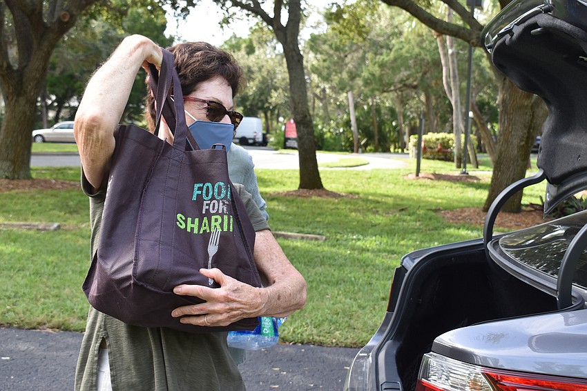Carole Cohen helps unload a car of donations.
