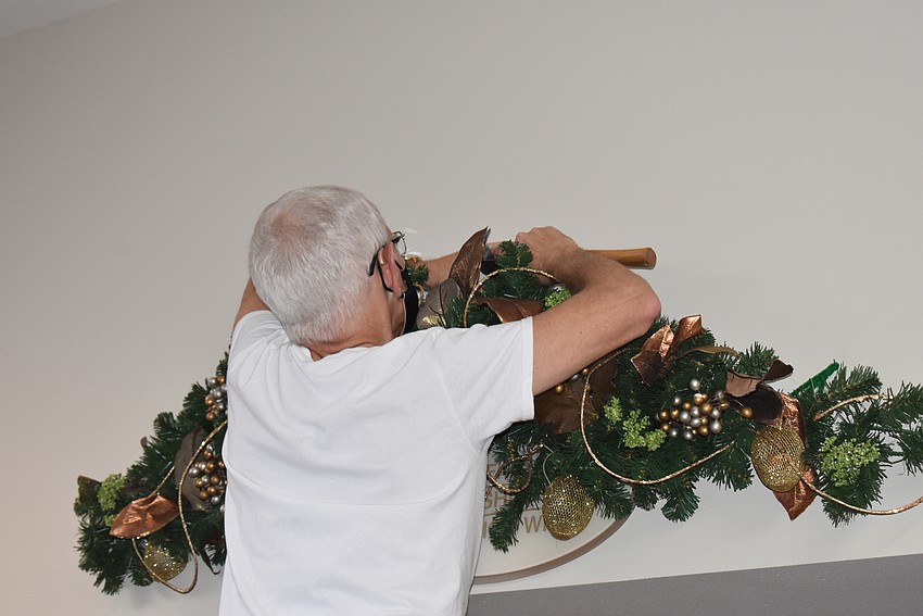 Steve Whalen hammers a garland into the wall.