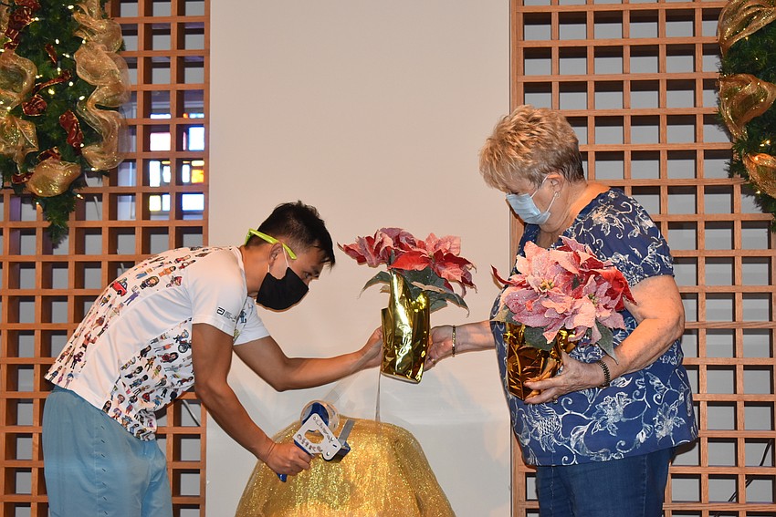 Ethan Ngo and Lynda Menuez tape poinsettias to the gold-festooned chairs.