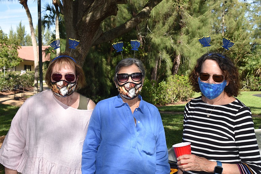 Maxine Tauber, Lois Lowsky and Karen Gary wear menorah headbands.