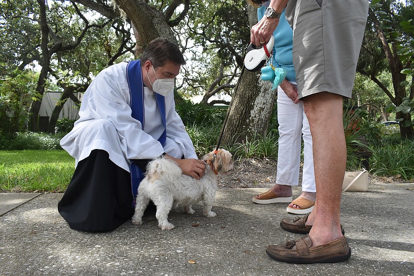 Father Dave Marshall blesses Oct. 8: Buddy Ortiz, as his humans, Ed and Mary, watch.