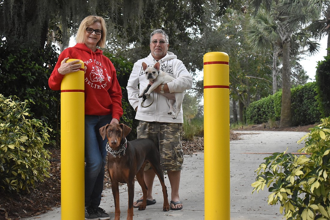 Heidi Easton (left) and Peter Easton take their 2-year-old Dobermann, Ollie, and 5-month-old French bulldog, Casper, for walks on this sidewalk by Adventure Place. The Eastons disagree on the CDD&#39;s decision to install bollards.