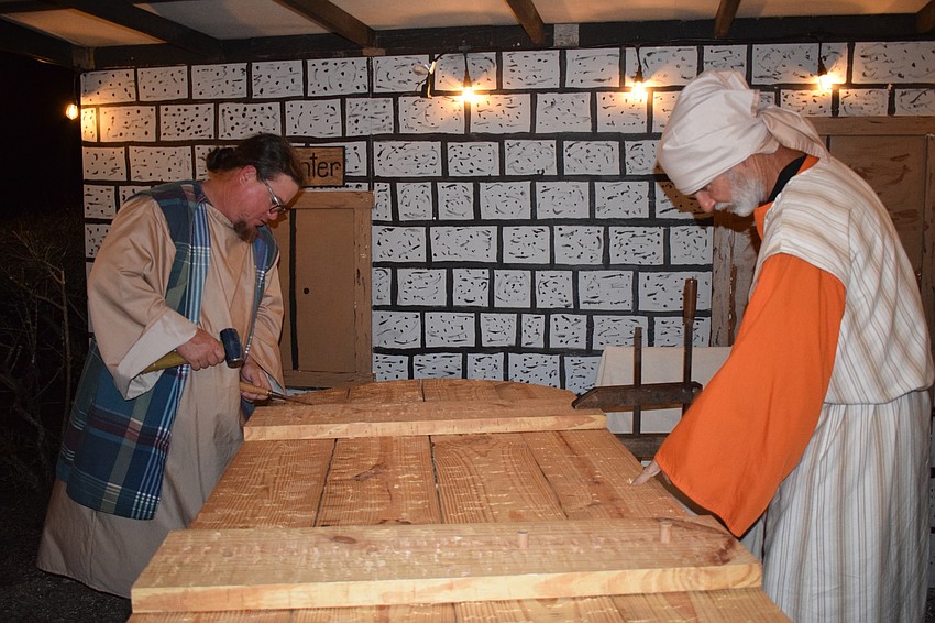 Mark Bulger and David Gay work on a wooden door as carpenters. In past years, they would help kids with a kids craft but can't this year due to the event being a drive-thru only. Bulger says it's weird not having the interaction.