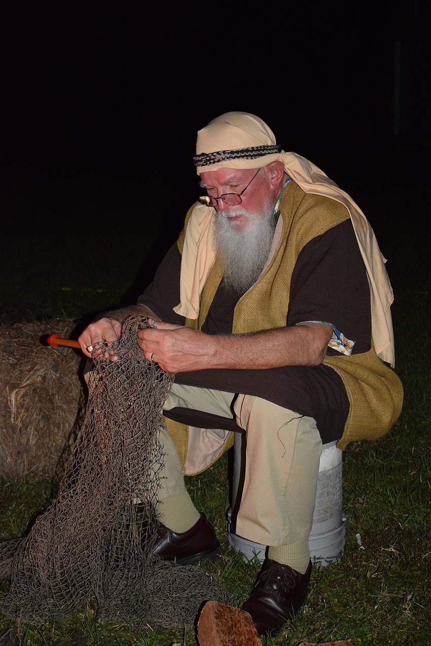 Sherman Mackereth, who is portraying a fisherman, works on fixing his fish net.