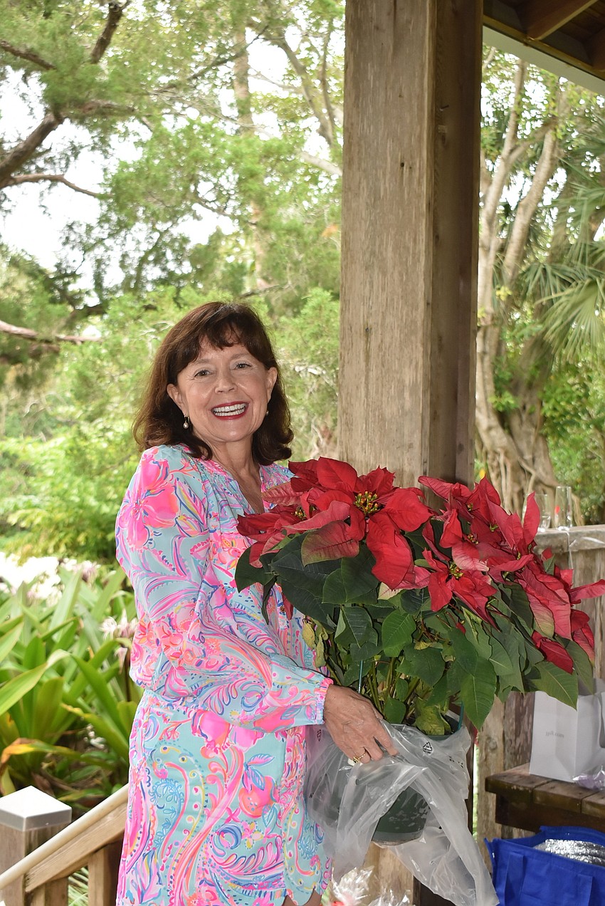 Kathryn Carr donates a poinsettia to be raffled off for the club.