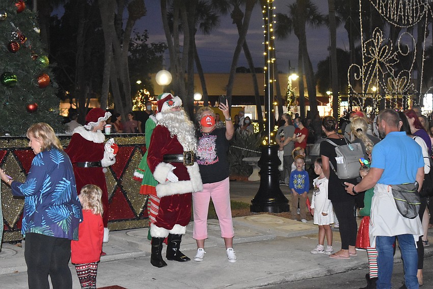 A woman snaps a selfie with Santa Claus as he fields greetings from admirers young and old.