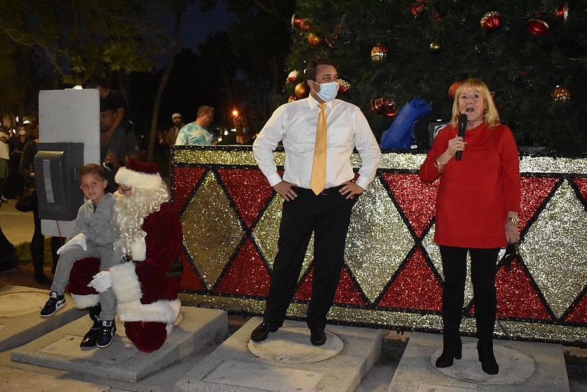 Anderson Amani sits on Santa's knee as Mayor Hagen Brody and Diana Corrigan address the crowd.
