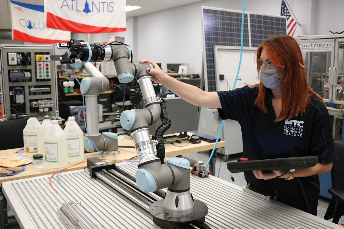 Samantha Sokolis, an Advanced Manufacturing student, adjusts a robot.