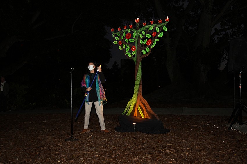 Lisa Feinman lights a large menorah as part of a Hanukkah celebration.
