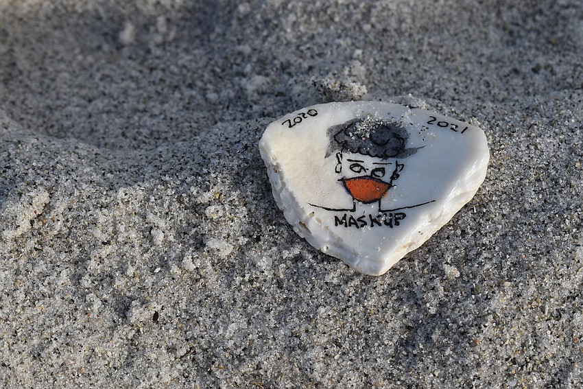 Treasure, not trash. A couple shell fragments painted with reminders to wear a mask were scattered on the sand.