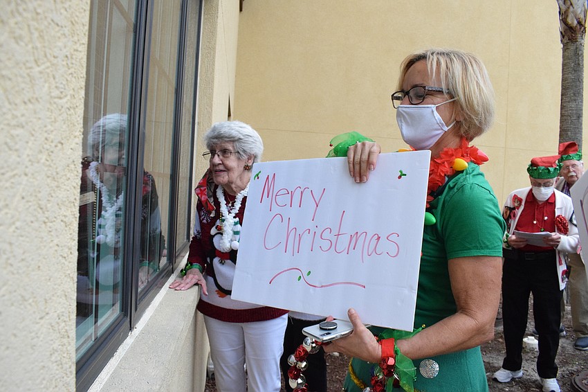 Nancee Dixon and Linda Britt-Smith, the activity coordinator at Cypress Springs Gracious Retirement Living, wish Rosie Breitwieser a Merry Christmas through Breitwieser's window.