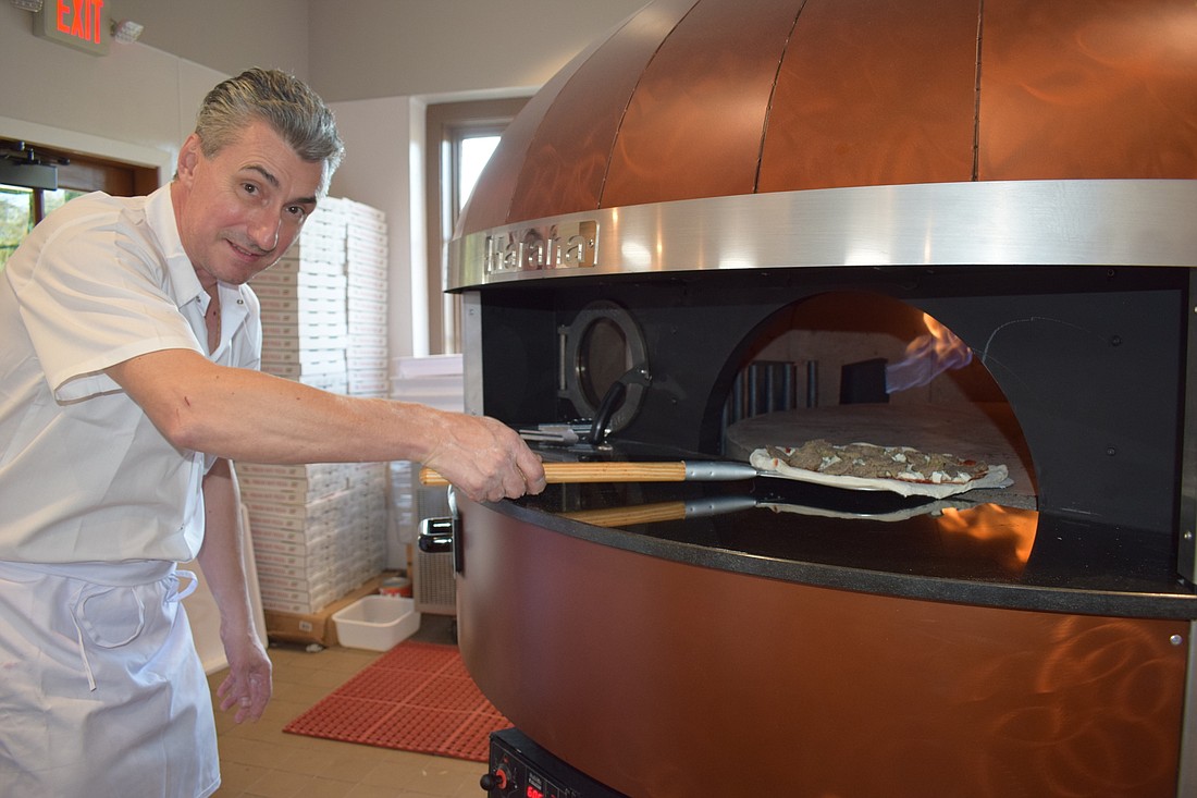 Chef Danny Barbos slides a pizza into what he calls the Lamborghini of pizza ovens, a Marana.