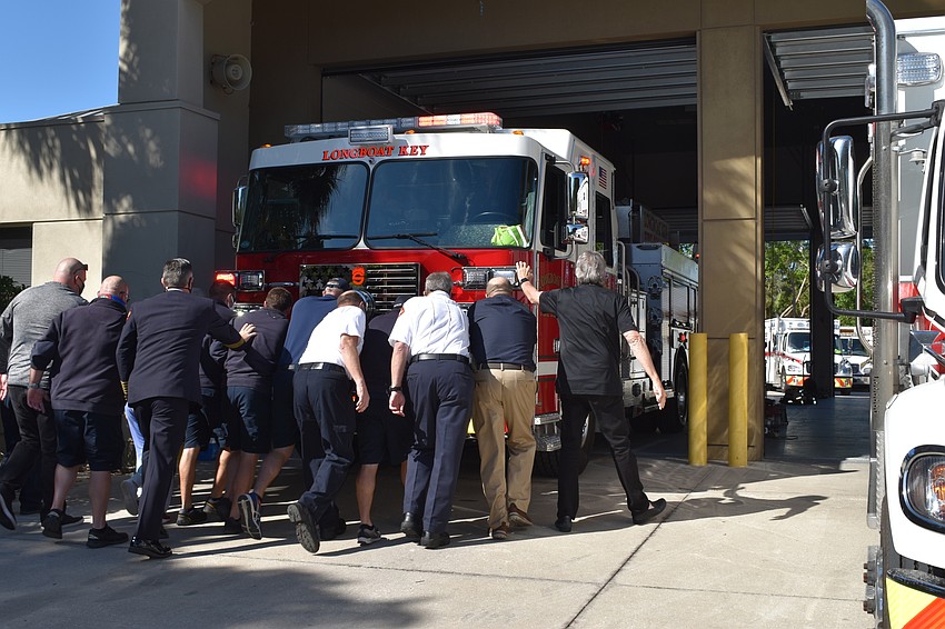 Longboat Key Fire Rescue personnel and town staff push the new fire truck into the bay at 5490 Gulf of Mexico Drive.