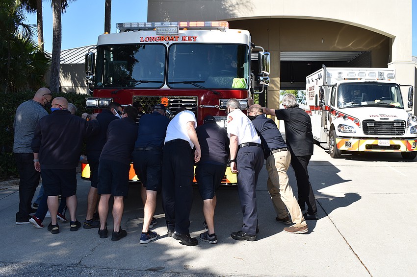 Longboat Key Fire Rescue personnel and town staff push the new fire truck into the bay at 5490 Gulf of Mexico Drive.