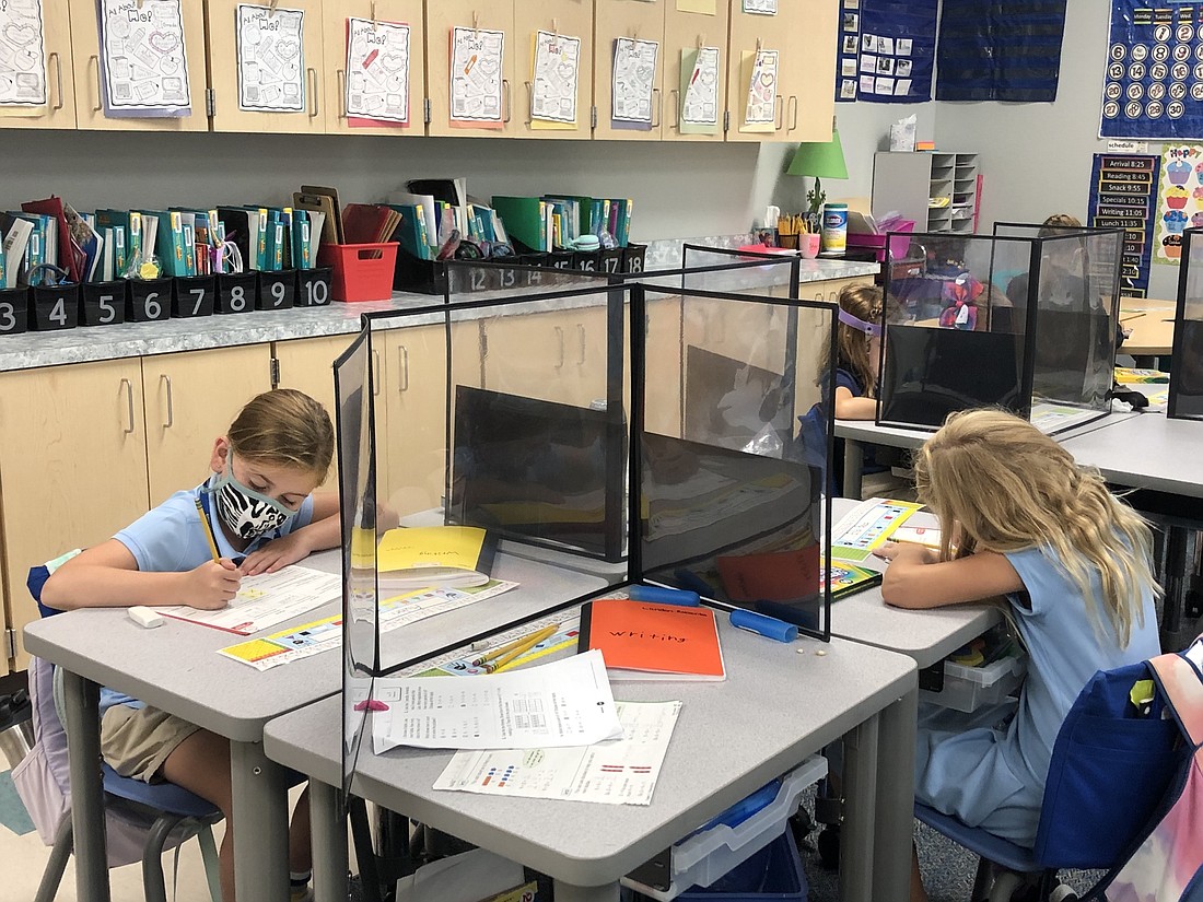 Robert E. Willis Elementary second graders Aubri Darpino and Ella Baas are socially distant while working on assignments. Schools will continue to practice social distancing as part of COVID-19 mitigation measures. File photo.