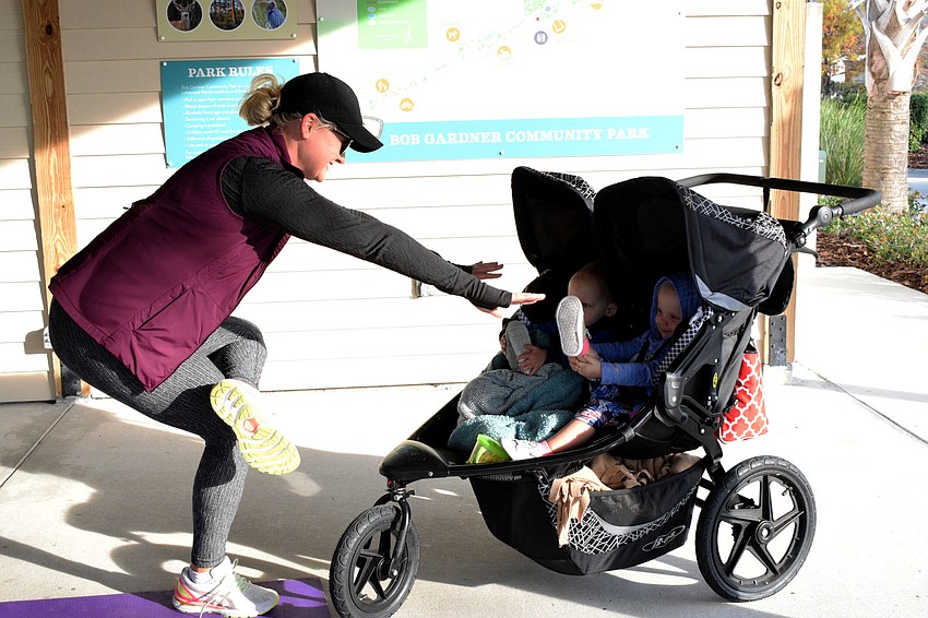 While Esplanade's RaeAnna Kalkert stretches, her 18-month-old children Hudson and Dakota Kalkert do the same in their stroller. Dakota Kalkert smiled as she reached for her toes.