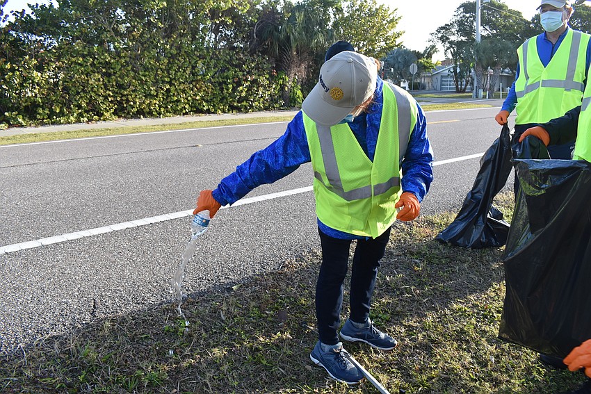 Jinx Kochan emptied water from a plastic bottle before putting it in the trash bag.