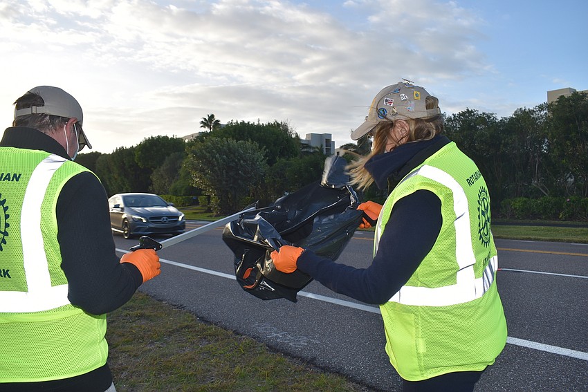 Bo Fuller aims for the trash bag Nancy Rozance attempts to keep safe from the wind.