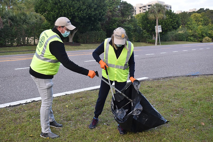 Bo Fuller puts trash into Nancy Rozance's garbage bag.
