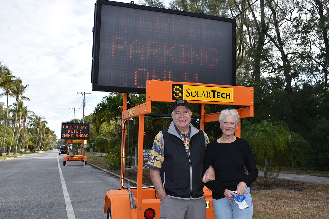 Pete and Carla Rowan pose for a photo by the town of Longboat Key&#39;s electronic sign that specifies Longbeach Village&#39;s resident permit parking.