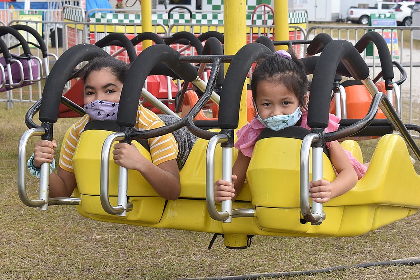 Sarasota residents Carla Cruz, 10, and Aubrey Chu, 7, prepare to start a ride that Cruz later said gave her butterflies. They were both excited to eat funnel cake later.