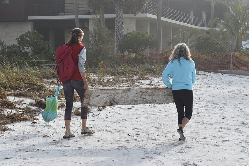 Cyndi Seamon and Lonna Smith remove a plank from the beach.