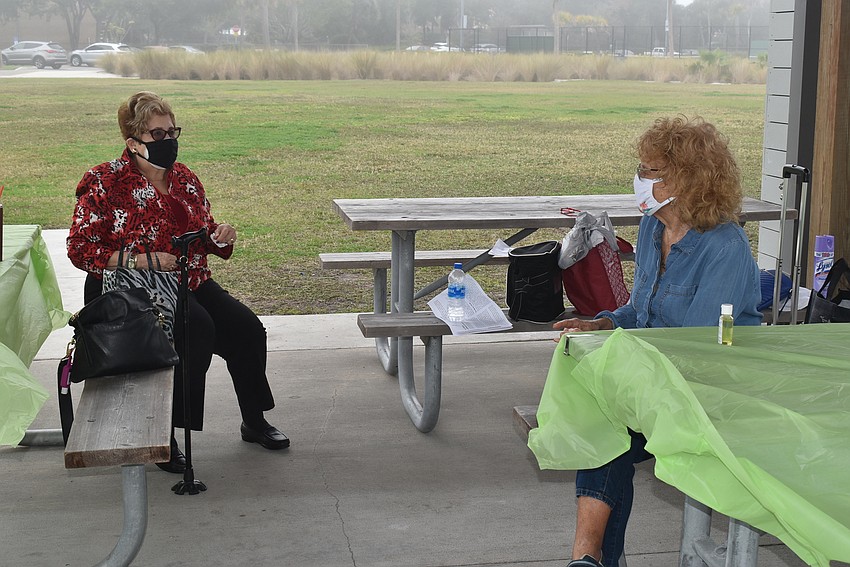 Elise Galinsky and Lois Barson chat from their separate tables.