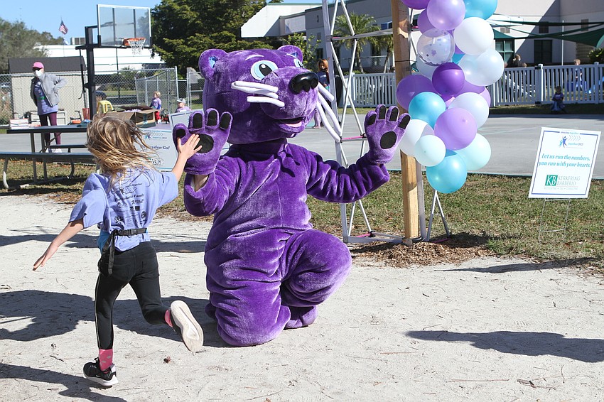 Menschy high fives students at the finish line.