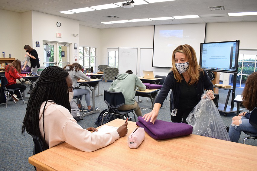 Freshman Amy Kwakye-Amoah receives a blanket from Melinda Lloyd. The Out-of-Door Academy is donating 875 blankets to shelters in Sarasota.