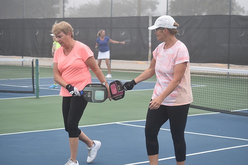 River Strand residents Cindy Cail and Deb Clawson tap rackets after losing a point. They have both been playing pickleball for about three years.