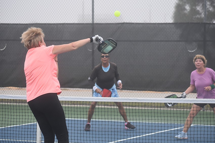 River Strand resident Cindy Cail hits the ball as Stonybrook resident Jacque Marks and River Strand resident Roxann Viera prepare to return. Marks and Viera beat Cail and River Strand resident Deb Clawson 15-14.