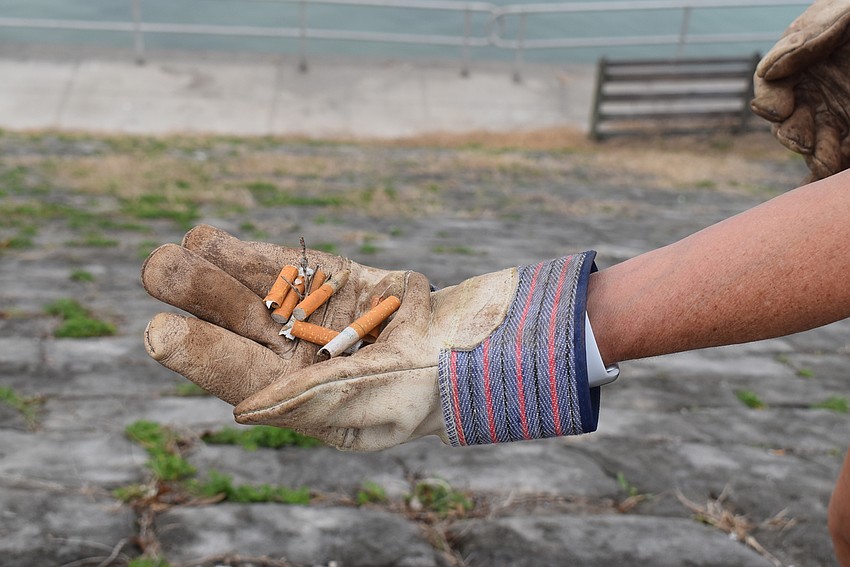 Karen Murray crouches to pick up cigarette butts.