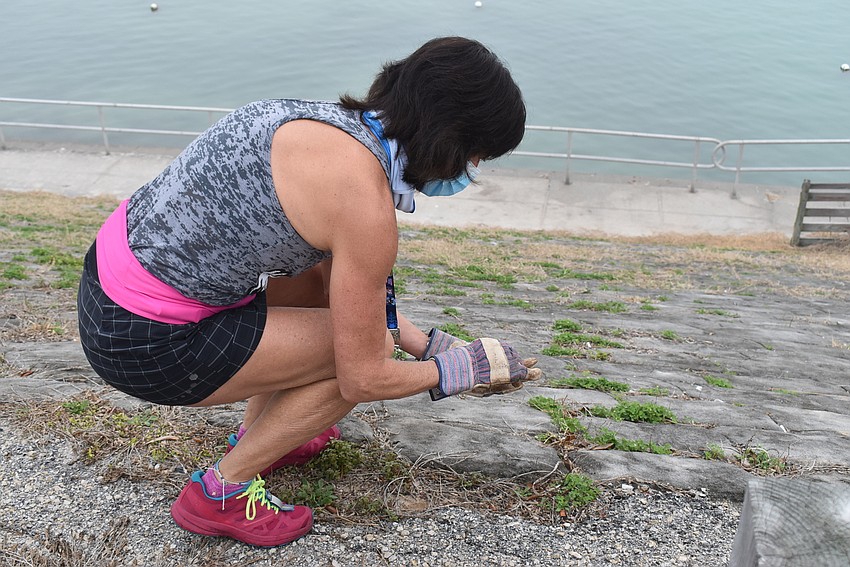 Karen Murray crouches to pick up cigarette butts.