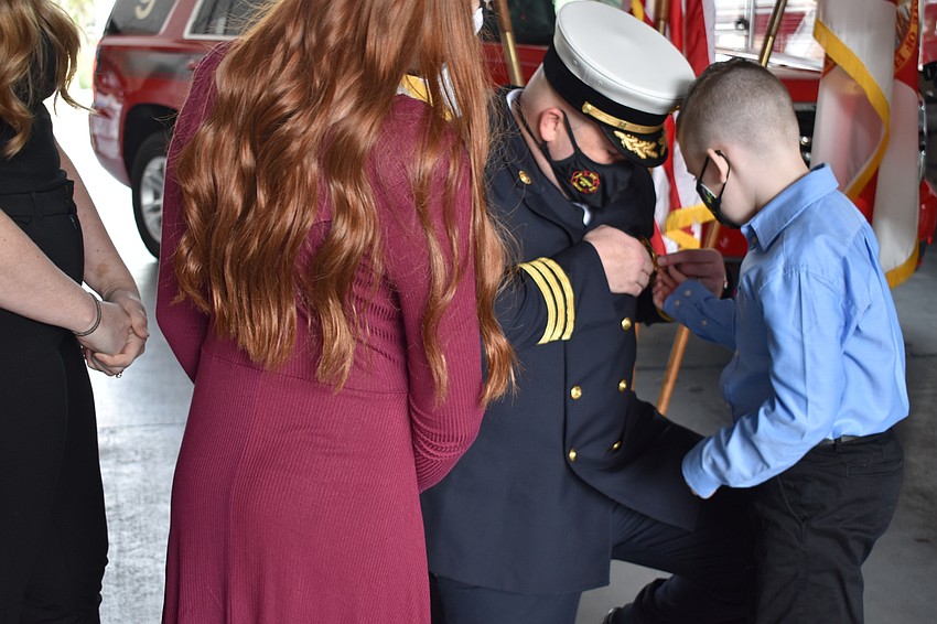 Newly-promoted Assistant Chief Bryan Carr's son Anderson pins him during Tuesday morning's ceremony.