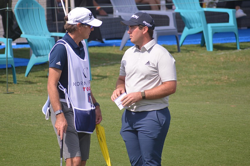 George Cunningham chats with his caddie after a par on the No. 18 hole. Cunningham finished eight under par and is tied for the tournament lead.