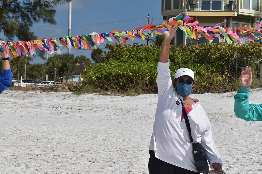 Judy Tobias lifts the string of ribbons. Lifting the ribbons was a way to symbolize elevating the memory of the lives lost and lift them to the sky.