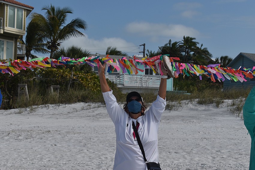 Judy Tobias lifts the string of ribbons. Lifting the ribbons was a way to symbolize elevating the memory of the lives lost and lift them to the sky.