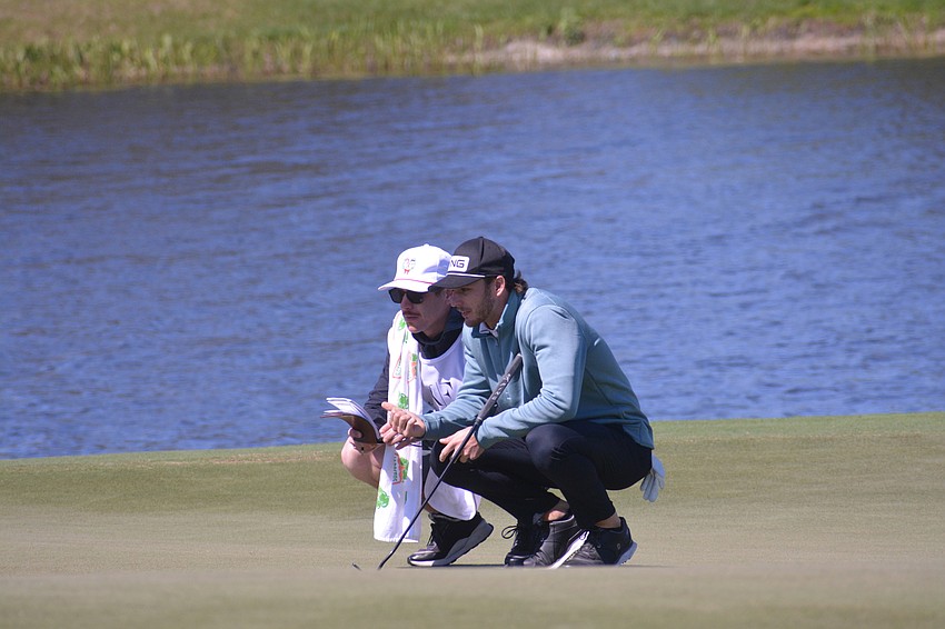 Brett Coletta consults with his caddie on the green of the No. 1 hole at Lakewood National Golf Club. Coletta would par the hole.