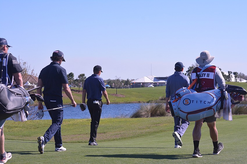 Paul Haley II, Steven Alker and Mark Hensby (plus their caddies) walk down the No. 18 hole to make their second shots.