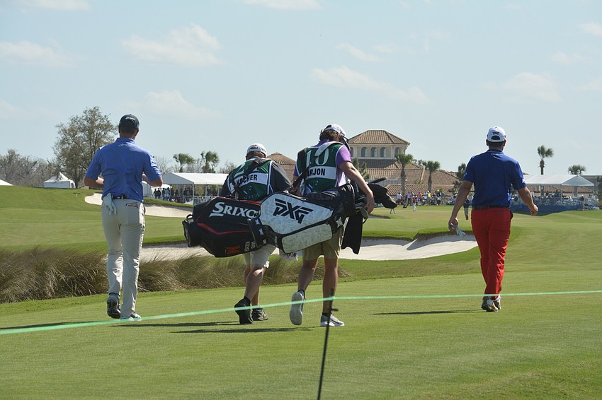 David Kocher, Paul Barjon and their caddies walk down the fairway on the No. 18 hole at Lakewood National Golf Club.