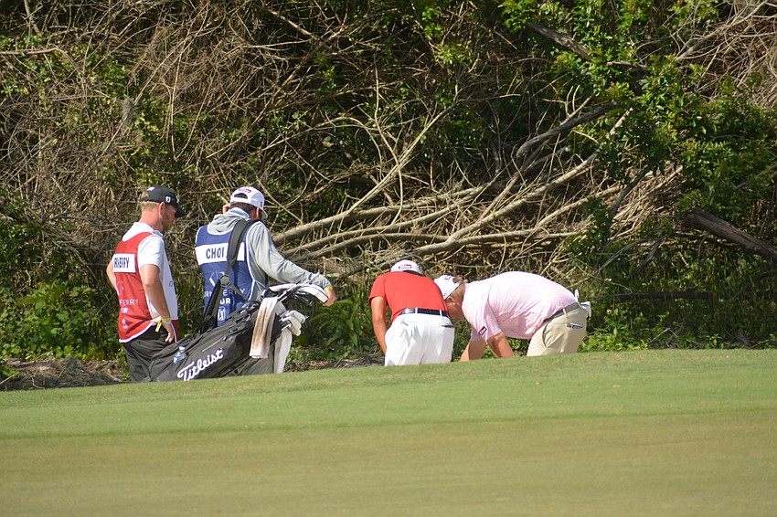 Albin Choi (red), Braden Thornberry (pink) and their caddies examine Thornberry's ball, which landed in a waste bunker, on the No. 17 hole. Thornberry would par the hole.