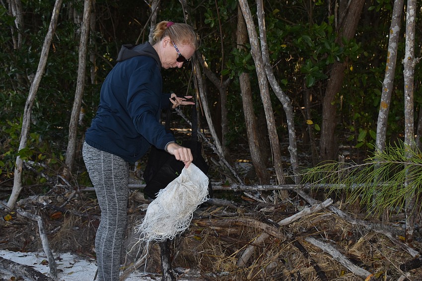 Carlyn Vigil shakes sand out of a sandbag remnant.