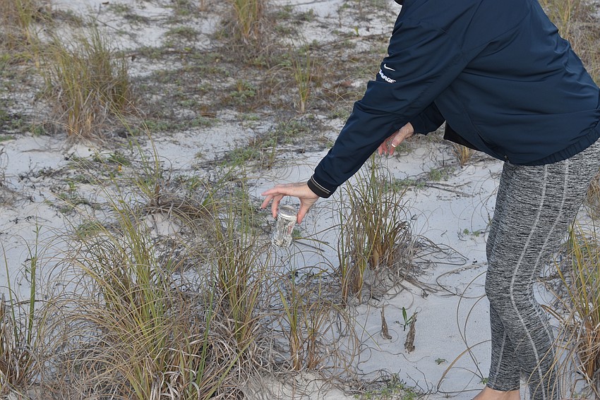 Carlyn Vigil shakes sand out of an old beer can.
