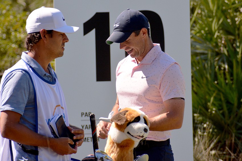 Rory McIlroy consults with his caddie before beginning his round Thursday. McIlroy would finish the round three under par.